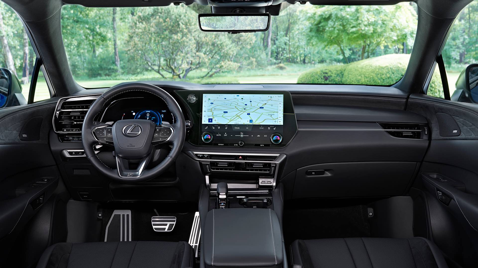 The interior view of a left hand drive Lexus RX. The multimedia screen is lit up with a map. The car is facing out to greenery.