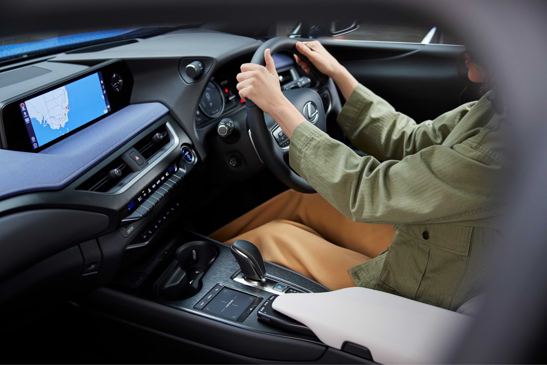 A lady sits behind the wheel of a UX 300e, showcasing its interior and multimedia screen.